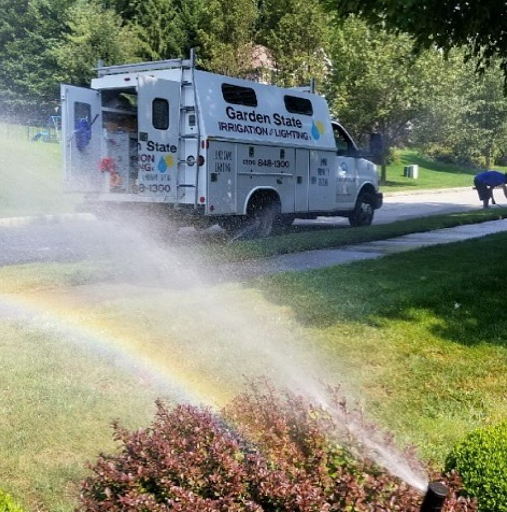 Garden State service vehicle beside an operating sprinkler