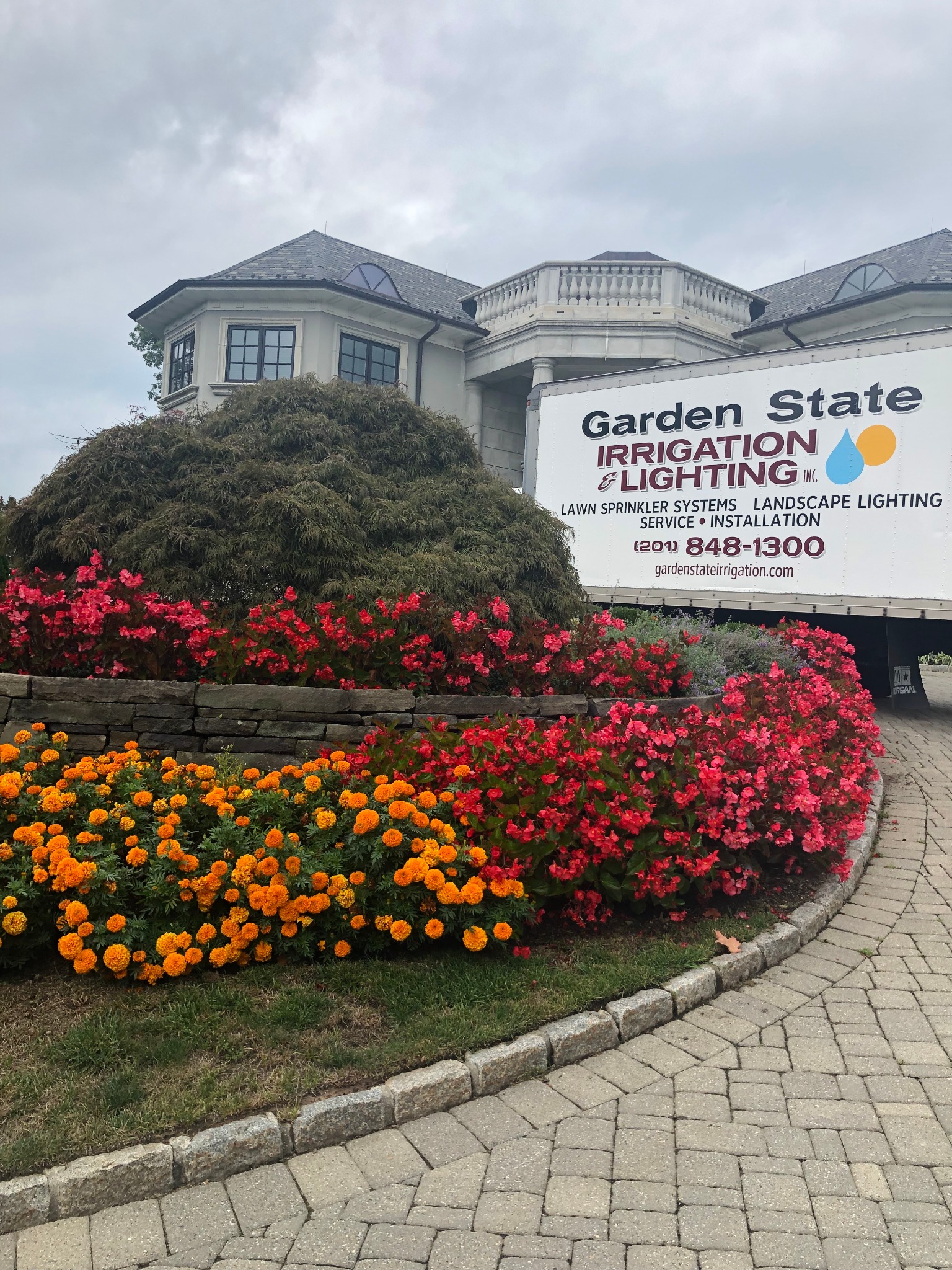 Garden State service truck beside colorful planting beds at a home