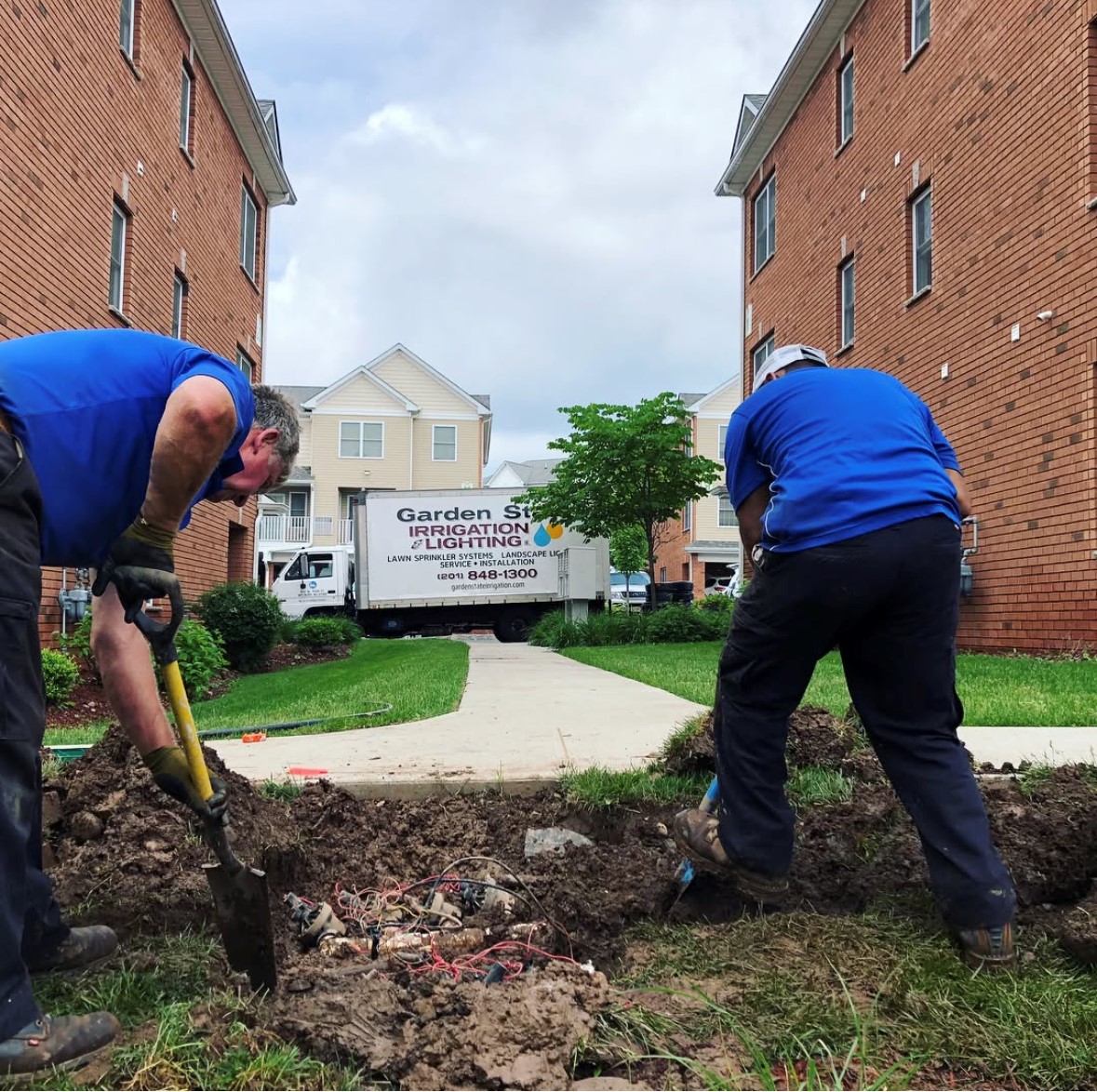 Garden State crew working on irrigation valves beside a walkway