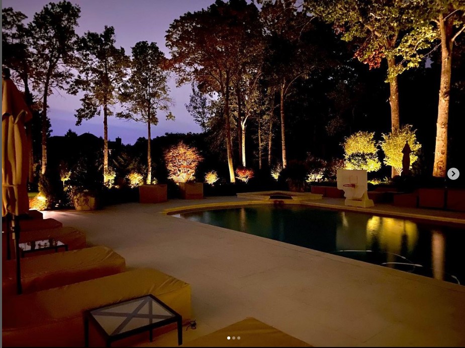 Warm uplighting surrounds a pool terrace at dusk