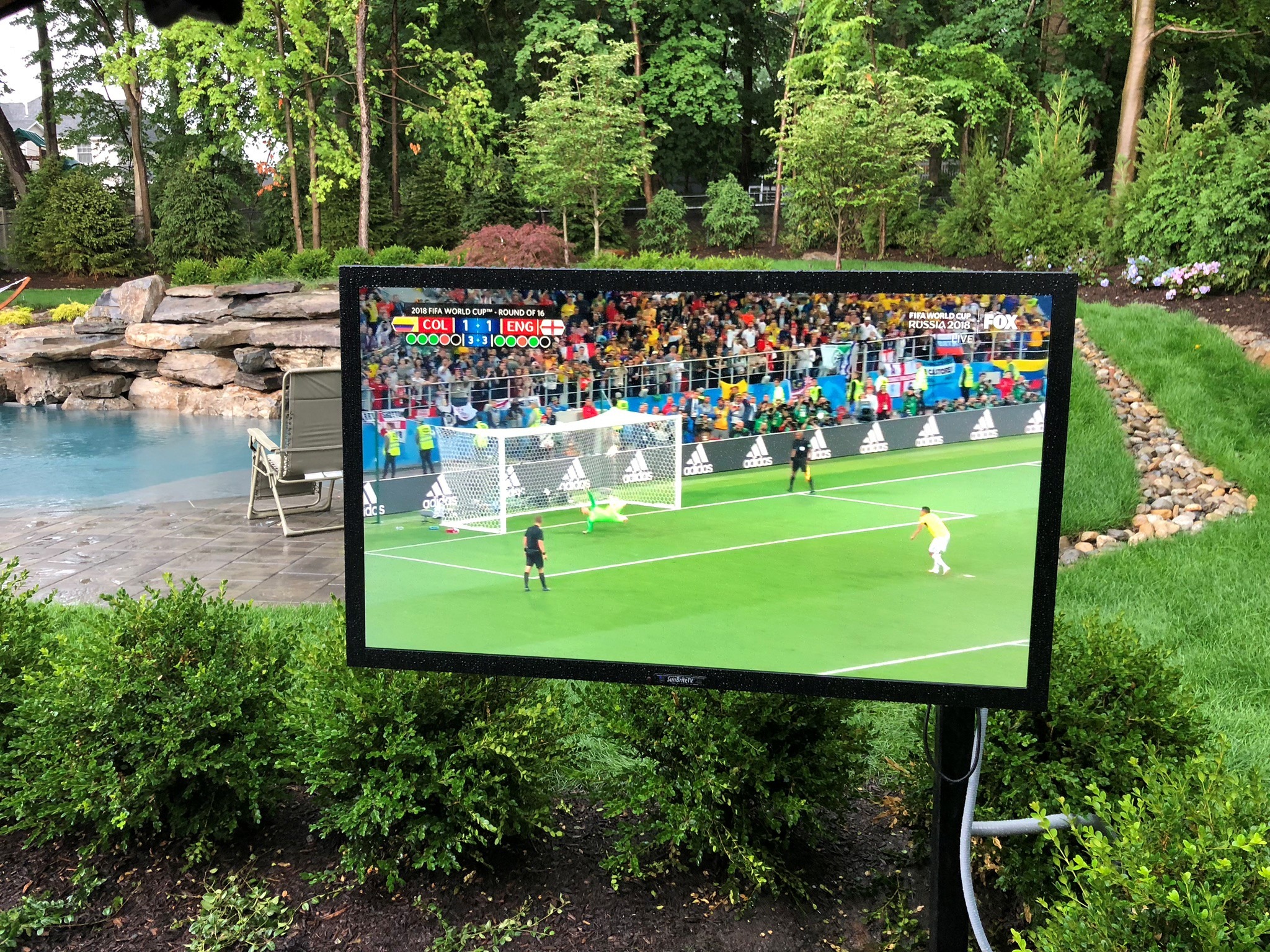 Outdoor television beside a landscaped pool